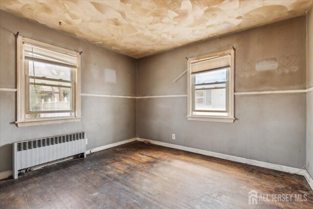399 Highland St, South Amboy, NJ 08879 - empty room featuring radiator, healthy amount of natural light, wood finished floors, and baseboards