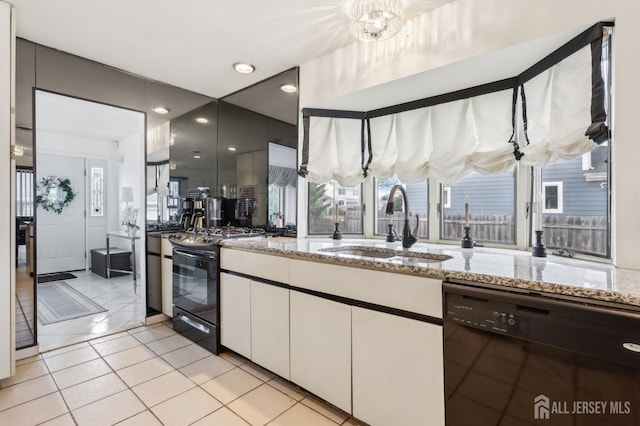 kitchen featuring black appliances, a sink, white cabinetry, light stone countertops, and light tile patterned floors