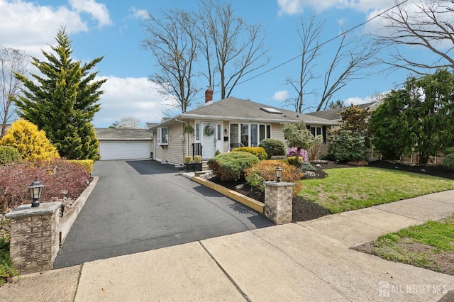 view of front of property with a front yard, a chimney, and a garage