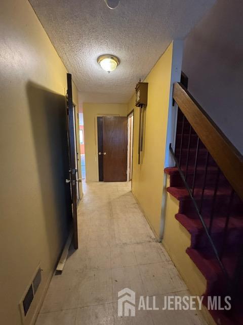 165 Penn Ct, Old Bridge, NJ 07747 - corridor featuring a textured ceiling, light flooring, and stairway