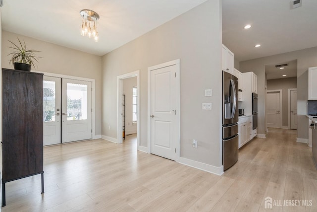 kitchen featuring stainless steel fridge, white cabinets, light wood-type flooring, and french doors