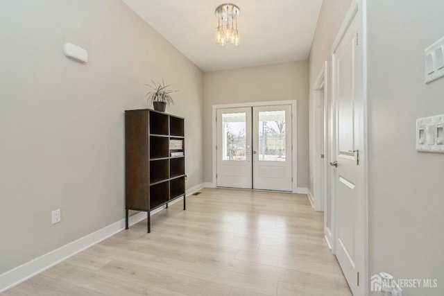 entryway with french doors, a chandelier, and light wood-type flooring