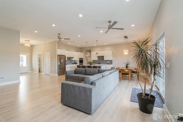 living room with ceiling fan, sink, and light hardwood / wood-style flooring