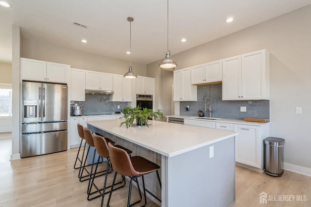 kitchen featuring sink, stainless steel appliances, white cabinets, and a kitchen island