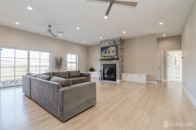 living room with ceiling fan, a fireplace, and light hardwood / wood-style flooring