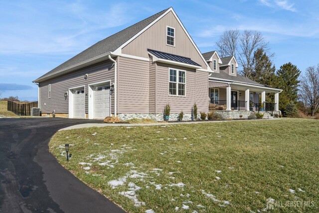 view of front of house featuring central AC, covered porch, a front yard, and a garage