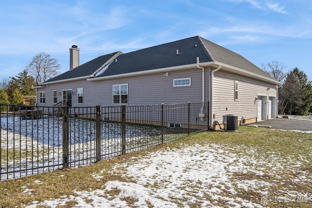 view of snow covered exterior featuring a garage and central AC unit