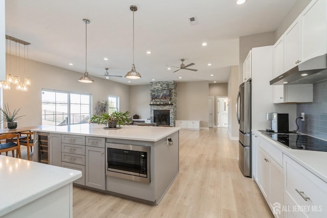 kitchen featuring stainless steel appliances, white cabinetry, a kitchen island, and decorative light fixtures