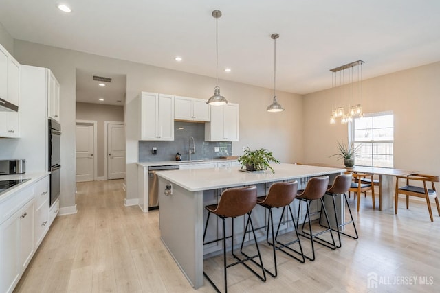 kitchen with white cabinetry, a kitchen island, sink, and pendant lighting