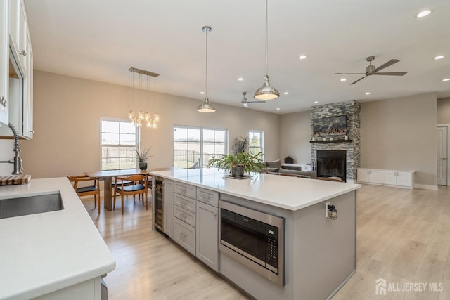 kitchen with stainless steel microwave, decorative light fixtures, a fireplace, and a center island