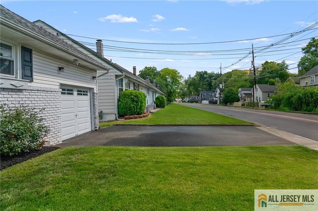 119 Brown Ave, Iselin, NJ 08830 - view of grassy yard featuring a garage and asphalt driveway
