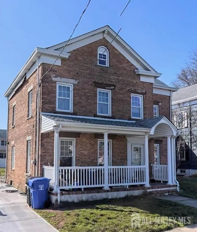 view of front of home with a porch and brick siding