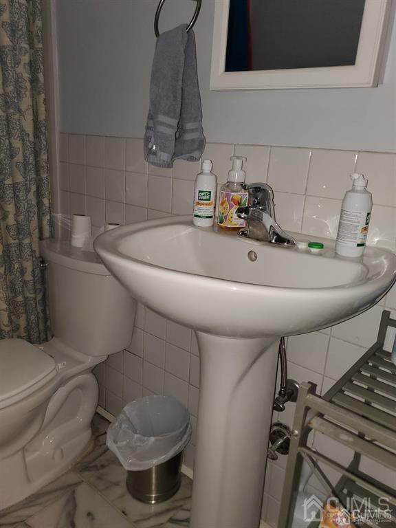 bathroom with tile walls and toilet