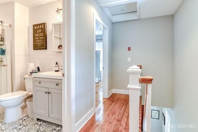 bathroom with wood finished floors, toilet, a shower stall, vanity, and tile walls