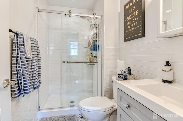 full bath featuring a shower stall, toilet, vanity, and tile walls