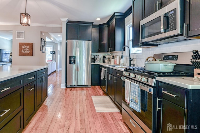 kitchen featuring appliances with stainless steel finishes, a sink, ornamental molding, light countertops, and decorative backsplash