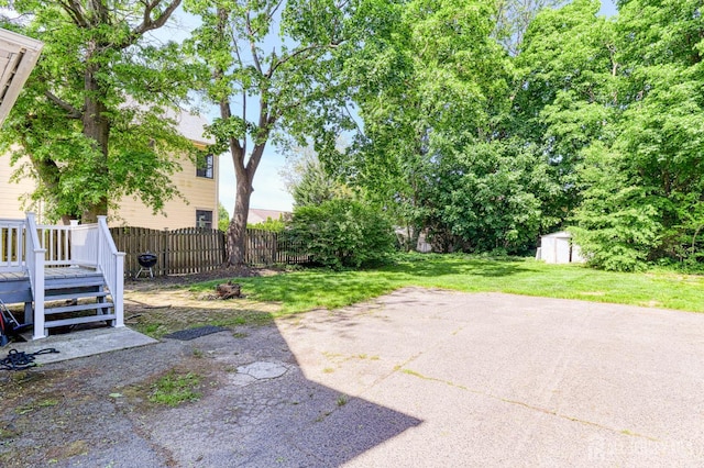 view of yard featuring a shed, an outdoor structure, a wooden deck, and a patio area