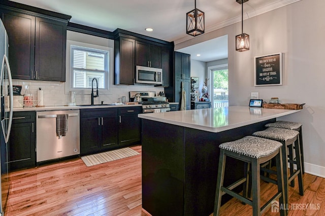 kitchen featuring stainless steel appliances, a sink, a kitchen bar, light wood-style floors, and tasteful backsplash