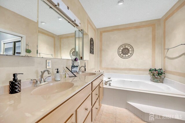 bathroom featuring a textured ceiling, tile patterned floors, tiled tub, and vanity