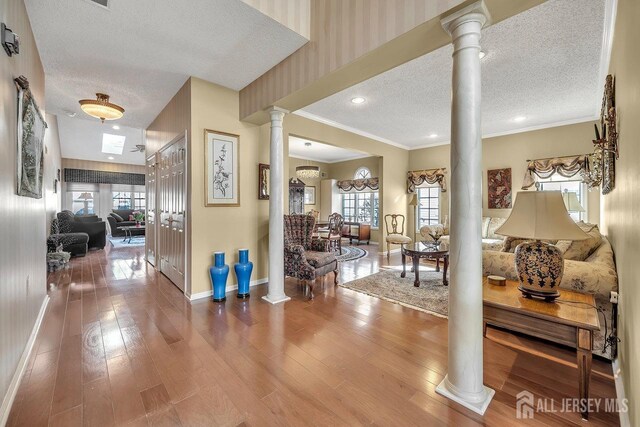 foyer featuring ornate columns, a textured ceiling, and a healthy amount of sunlight