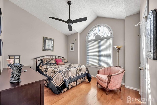 bedroom featuring lofted ceiling, multiple windows, ceiling fan, and light wood-type flooring