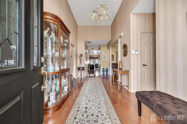 foyer with a textured ceiling, an inviting chandelier, and hardwood / wood-style floors