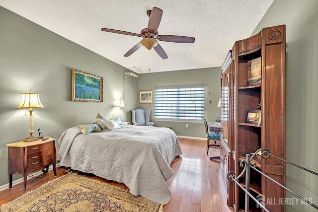 bedroom featuring hardwood / wood-style flooring, a textured ceiling, and ceiling fan