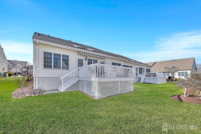 rear view of property with a wooden deck and a lawn