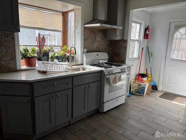 220 S Washington Ave, Dunellen, NJ 08812 - kitchen featuring wall chimney range hood, white range with gas cooktop, tasteful backsplash, gray cabinetry, and wood finished floors