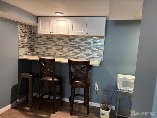 220 S Washington Ave, Dunellen, NJ 08812 - bar with white microwave, decorative backsplash, and wood finished floors