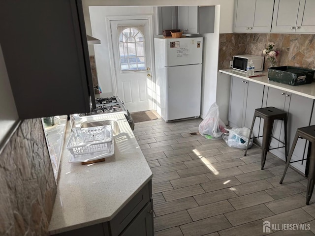 220 S Washington Ave, Dunellen, NJ 08812 - kitchen featuring white appliances, tasteful backsplash, wood tiled floors, light stone counters, and gray cabinets