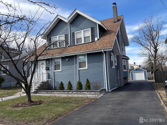 220 S Washington Ave, Dunellen, NJ 08812 - view of front of house with asphalt driveway, a chimney, a garage, an outbuilding, and roof with shingles