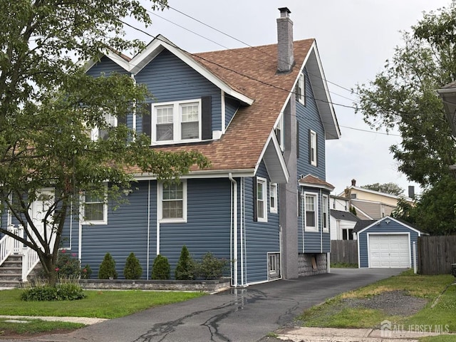 220 S Washington Ave, Dunellen, NJ 08812 - view of side of property featuring a detached garage, an outbuilding, asphalt driveway, a shingled roof, and a chimney