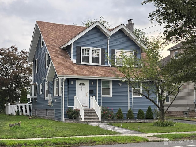 220 S Washington Ave, Dunellen, NJ 08812 - view of front facade with a chimney, a front yard, and a shingled roof