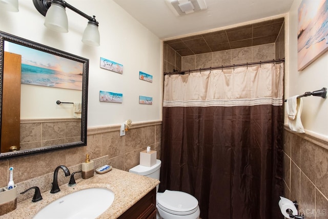 bathroom with tile walls, toilet, vanity, and walk in shower