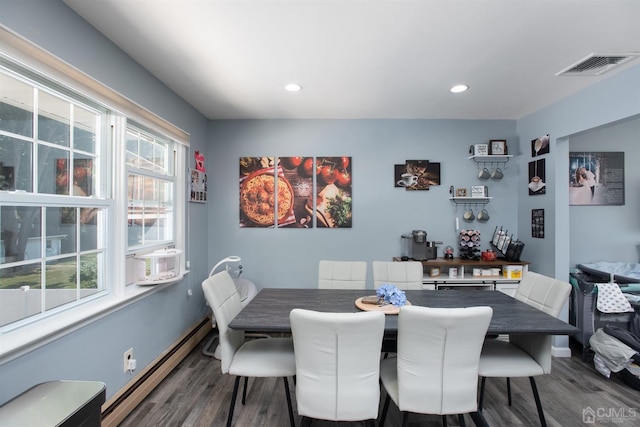 dining area featuring a baseboard heating unit, a wealth of natural light, and hardwood / wood-style floors