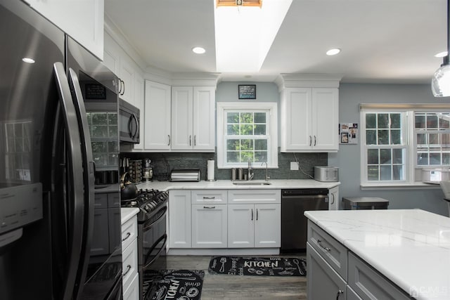 kitchen with white cabinetry, wood-type flooring, light stone countertops, black appliances, and sink