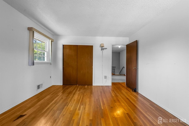 85 Hidden Lake Dr, North Brunswick, NJ 08902 - unfurnished bedroom with hardwood / wood-style floors, a textured ceiling, and a closet