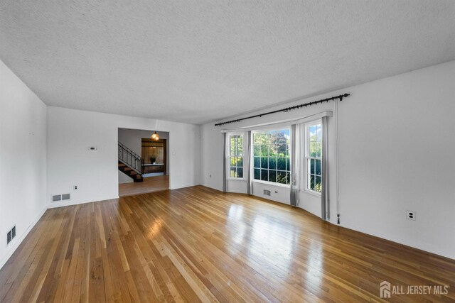 85 Hidden Lake Dr, North Brunswick, NJ 08902 - unfurnished living room featuring a textured ceiling, wood-type flooring, and stairway