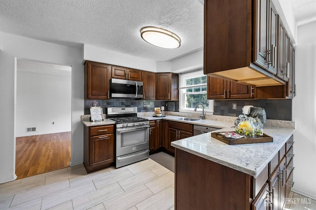 85 Hidden Lake Dr, North Brunswick, NJ 08902 - kitchen featuring appliances with stainless steel finishes, tasteful backsplash, light stone countertops, a peninsula, and a textured ceiling