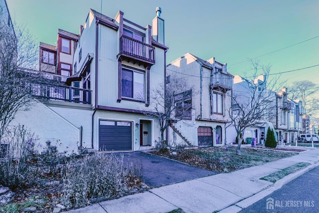 view of front of home with a balcony, driveway, and a garage