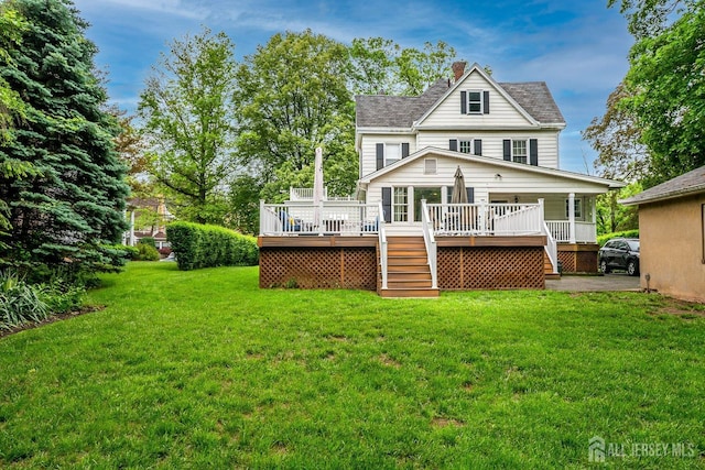 back of property featuring stairs, a chimney, a deck, and a lawn