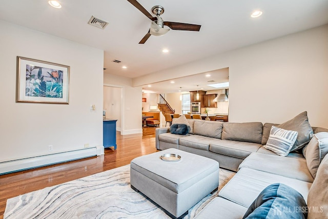 living area with light wood-style flooring, recessed lighting, a ceiling fan, a baseboard radiator, and baseboards