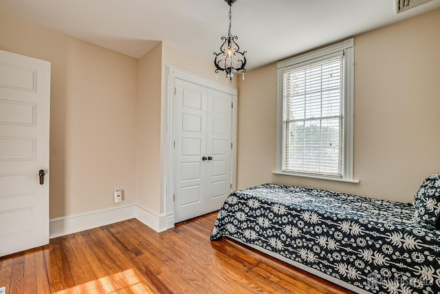 bedroom featuring wood finished floors, a chandelier, and baseboards