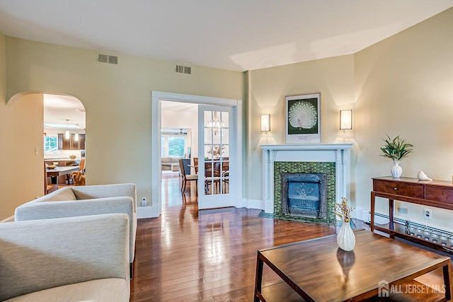 living area featuring hardwood / wood-style flooring, arched walkways, a fireplace, and baseboards