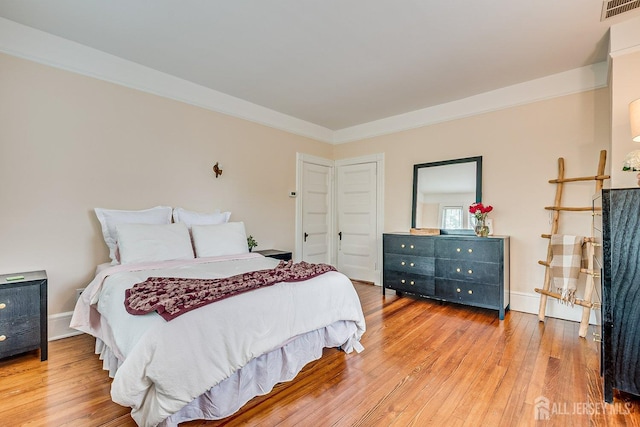 bedroom with light wood finished floors and ornamental molding