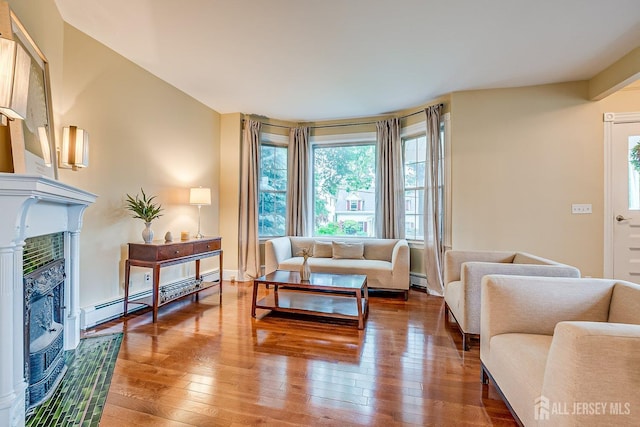 living room with hardwood / wood-style flooring, a glass covered fireplace, and baseboard heating