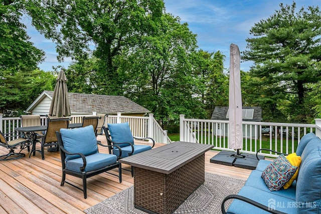 wooden terrace with outdoor dining area, an outdoor hangout area, view of wooded area, and an outbuilding