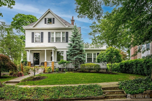 view of front of home with covered porch, a chimney, and a front lawn