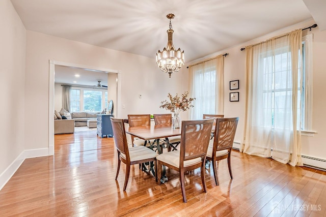 dining space featuring a chandelier, light wood finished floors, and baseboards